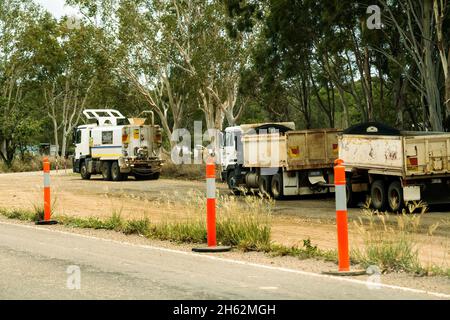 Bruce Highway Mackay a Townsville, Queensland, Australia - Novembre 2021: Camion di carting suolo e un altro per innaffiare la polvere parcheggiata in su ai contro di strada Foto Stock