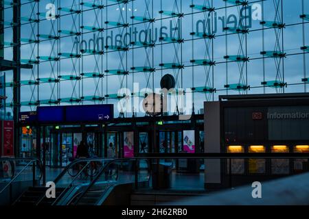 germania, berlino, la stazione orologio al mattino presto nella stazione principale di fronte alla facciata di vetro Foto Stock