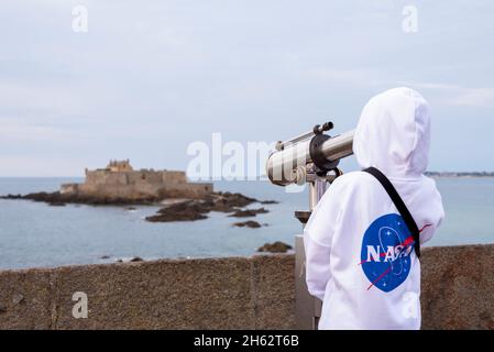 francia,bretagna,ille et vilaine,saint malo,ragazzo guarda attraverso un telescopio fino all'isola marea di petit-bé con il forte nazionale, costa atlantica Foto Stock