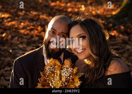 Emozionale, piena di amore foto di una coppia ben vestita gara mista abbracciare e tenere baciare l'un l'altro al tramonto in un parco della città di Vancouver, Britis Foto Stock