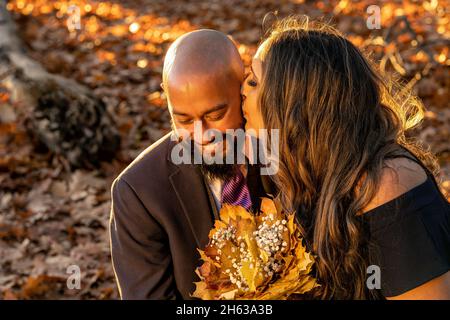 Emozionale, piena di amore foto di una coppia ben vestita gara mista abbracciare e tenere baciare l'un l'altro al tramonto in un parco della città di Vancouver, Britis Foto Stock