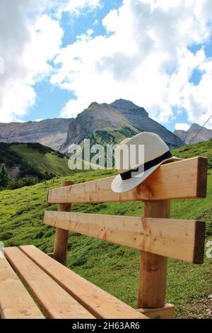 plumsjoch (1650m) sullo sfondo il vorgipfel e le bettlerkarspitze (2268 m) a destra di esso la schaufelspitze e la cresta di discesa, nel eng nei monti karwendel,rißbachtal,tirolo,austria,europa,alm,eng-alm in primo piano una panchina con un cappello Foto Stock