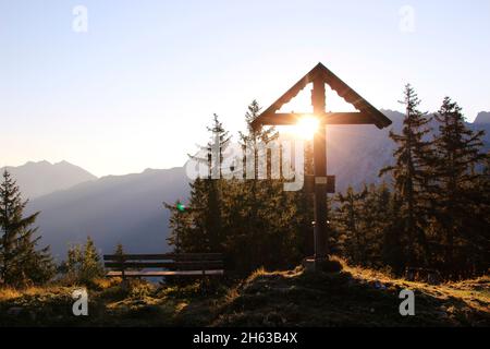 al mattino rugiada alle montagne ci si sposta, mattina escursione al grünkopf (1587 m), panchina di fronte a grünkopfkreuz, europa, germania, baviera, alta baviera, werdenfelser terra, valle isar, mittenwald, sole, luce posteriore Foto Stock