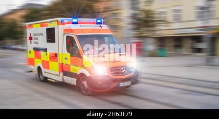 un'ambulanza dalla croce rossa attraversa augusta con luci lampeggianti e alta velocità Foto Stock