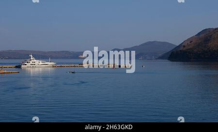 grecia,isole greche,isole ionie,cefalonia,lioxouri,traghetto da argostoli a lixouri,fotografato dal traghetto,uscita dal golfo di argostoli,vista di bianco yacht di lusso giacente sul molo Foto Stock