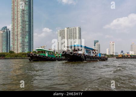 due rimorchiatori tirano una grande piattaforma sul fiume chao phraya, skyline, bangkok, thailandia, asia Foto Stock