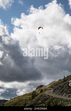 un parapendio in volo sul thurntaler rundweg di fronte a nuvole di tempesta, città valle di sillian, montagne villgraten, tirolo orientale, distretto di lienz, tirolo, austria Foto Stock