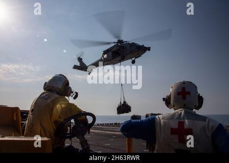 GOLFO D'OMAN (NOV. 11, 2021) Aviation Boatswain’s Mate (Handling) Airman Corey Martin, Left, and Hospital Corpsman 3rd Class Kent Martin guardare un MH-60S Sea Hawk elicottero attaccato al Sea Combat Squadron elicottero 21 disporre forniture sul ponte di volo della nave da assalto anfibio USS Essex (LHD 2) Durante un rifornimento verticale-a-mare con il carico asciutto e la nave di munizioni USNS Cesar Chavez (T-AKE 14), novembre 11. L'Essex e l'undicesima unità di spedizione marina sono dislocate nell'area della 5th Fleet degli Stati Uniti di operazioni a sostegno delle operazioni navali per garantire la stabilità e la sicurezza marittima nella CE Foto Stock