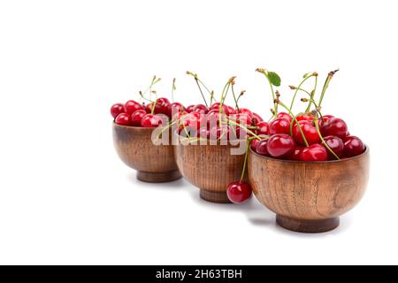 Linea di ciliegie rosso scuro in un piatto di legno su sfondo bianco. Isolato su ciliegio bianco Foto Stock