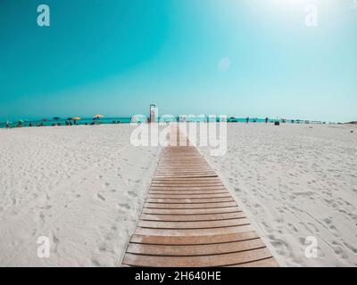 pov e prima vista della persona che cammina in una spiaggia bianca che guarda al mare blu o oceano in una giornata di sole di vacanza Foto Stock