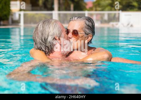 coppia di due anziani felici divertirsi e divertirsi insieme in piscina sorridendo e giocando. persone felici godersi l'estate all'aperto in acqua Foto Stock