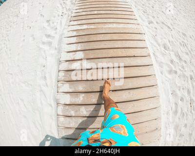 pov e prima vista della persona che cammina in una spiaggia bianca che guarda al mare blu o oceano in una giornata di sole di vacanza Foto Stock