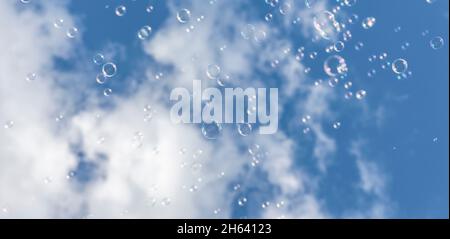 bolle di sapone di fronte a un cielo bianco-blu Foto Stock