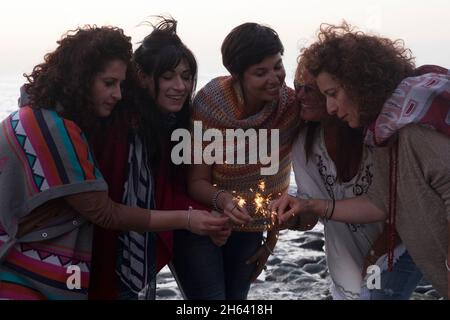 le donne gruppo di amici di potere hanno divertimento insieme nell'amicizia che illumina il fuoco sparkler all'aperto - le giovani donne adulte celebrano e si divertono con il cielo bianco sullo sfondo Foto Stock