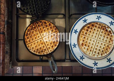 ferro da stiro con waffle appena sfornati in cucina Foto Stock