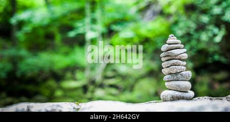 cairn nella foresta su uno sfondo verde sfocato Foto Stock