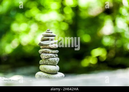 cairn nella foresta su uno sfondo verde sfocato Foto Stock