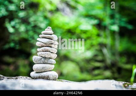 cairn nella foresta su uno sfondo verde sfocato Foto Stock