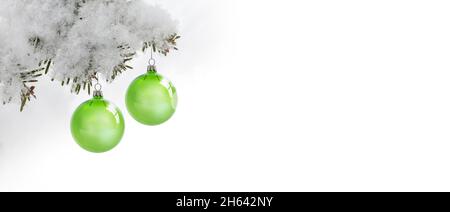 due palle verdi di natale su un ramo di pino innevato Foto Stock