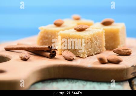 Halava, dolci di farina indiana tagliati in quadrati decorati con mandorle su tavola di legno vista laterale primo piano Foto Stock