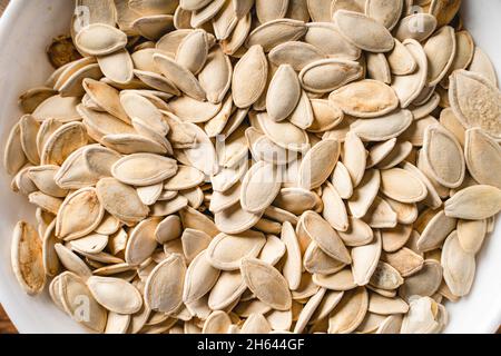 Vista dall'alto sui semi di zucca tostati salati freschi nella ciotola sul tavolo Foto Stock