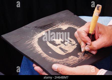 creazione di disegni su tavola nera con coltello artigianale Foto Stock