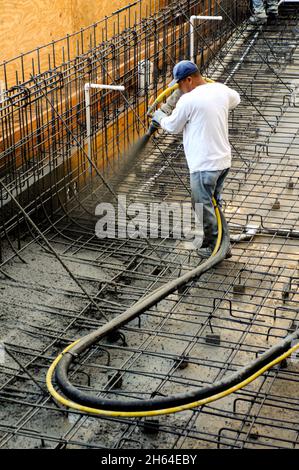 Il lavoratore di costruzione spruzzando shotcrete su acciaio di rinforzo per formare una nuova piscina Foto Stock