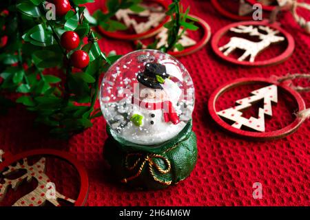 Souvenir di Natale con pupazzo di neve. Decorazioni natalizie in legno su sfondo rosso Foto Stock