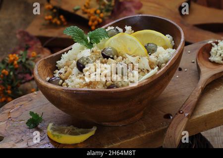 Couscous con limone, formaggio, uva e menta su un tavolo di legno Foto Stock