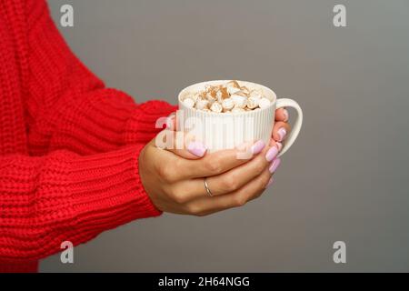 Gustatevi cioccolata calda o cacao con marshmallows: Tazza da presa femminile con bevanda calda invernale o autunnale Foto Stock