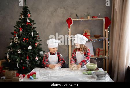 Cucinare i biscotti di natale a casa, i panettieri dei bambini impastano la pasta del pan di zenzero, preparare il cibo la vigilia di natale, fratello e sorella amichevoli Foto Stock