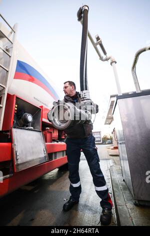 Itzehoe, Germania. 9 novembre 2021. Un dipendente di un'azienda di gasolio e olio di riscaldamento è in possesso di un bocchettone di rifornimento per riempire il suo camion cisterna sulla proprietà dell'azienda. Credit: Christian Charisius/dpa/Alamy Live News Foto Stock