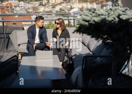 Uomo e donna che parlano sul balcone sul tetto dell'edificio Foto Stock