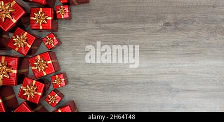 Regali di Natale rossi con archi dorati visti dall'alto. Legno sfondo - rendering 3D Foto Stock