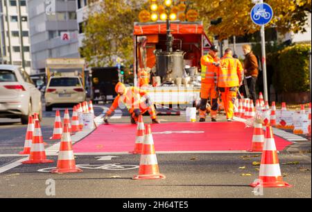 10 novembre 2021, Hessen, Francoforte sul meno: I lavoratori hanno tracciato una pista ciclabile con vernice rossa. In Gartenstraße/Walter-Kolb-Straße un percorso ciclabile è contrassegnato con vernice rossa. Foto: Andreas Arnold/dpa Foto Stock