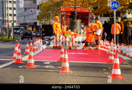 10 novembre 2021, Hessen, Francoforte sul meno: I lavoratori hanno tracciato una pista ciclabile con vernice rossa. In Gartenstraße/Walter-Kolb-Straße un percorso ciclabile è contrassegnato con vernice rossa. Foto: Andreas Arnold/dpa Foto Stock