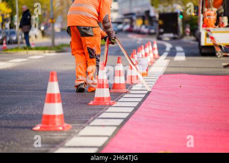 10 novembre 2021, Hessen, Francoforte sul meno: I lavoratori hanno tracciato una pista ciclabile con vernice rossa. In Gartenstraße/Walter-Kolb-Straße un percorso ciclabile è contrassegnato con vernice rossa. Foto: Andreas Arnold/dpa Foto Stock