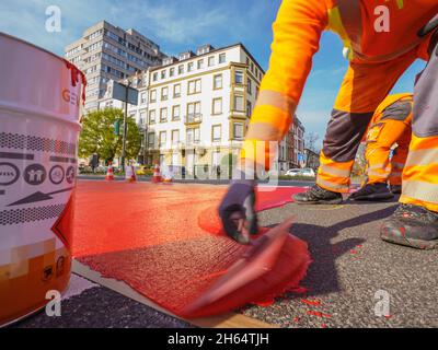 10 novembre 2021, Hessen, Francoforte sul meno: Un operaio dipinge la vernice rossa per la pista ciclabile. In Gartenstraße/Walter-Kolb-Straße un percorso ciclabile è contrassegnato con vernice rossa. Foto: Andreas Arnold/dpa Foto Stock