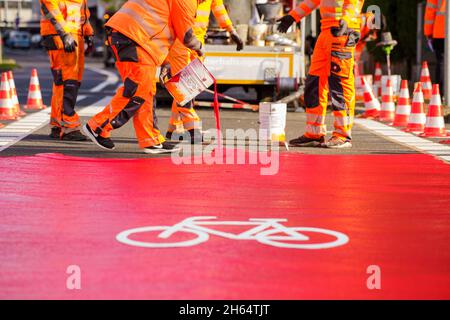 10 novembre 2021, Hessen, Francoforte sul meno: I lavoratori hanno tracciato una pista ciclabile con vernice rossa. In Gartenstraße/Walter-Kolb-Straße un percorso ciclabile è contrassegnato con vernice rossa. Foto: Andreas Arnold/dpa Foto Stock