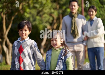 happy famiglia asiatica con due bambini che si prendono una passeggiata all'aperto nel parco della città Foto Stock