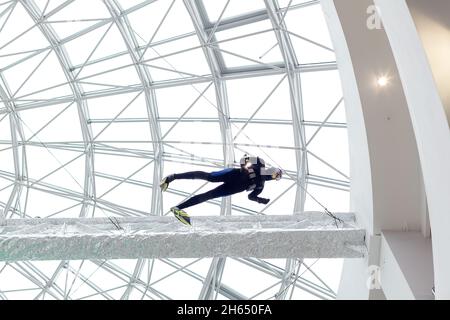 Sotto il tetto di vetro dell'edificio è appeso un manichino in una tuta subacquea. Foto Stock