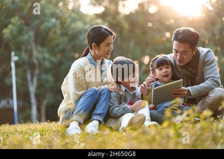 famiglia asiatica con due bambini che si rilassa all'aperto nel parco cittadino Foto Stock