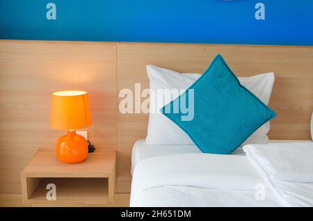 Cuscini blu e lampade arancioni sul letto. Foto Stock