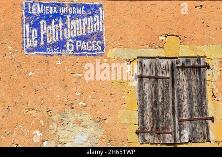 Monpazier, Francia. Giugno 2015. Vecchia parete con intemperie dipinte pubblicità e vecchie persiane. Foto di alta qualità Foto Stock