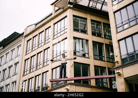 Scultura di un uomo in piedi sul bar vicino a un edificio moderno. Monaco di Baviera Foto Stock