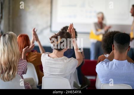 Gruppo di giovani creativi applaude a una presentazione ben tenuta in un'atmosfera piacevole in ufficio Foto Stock