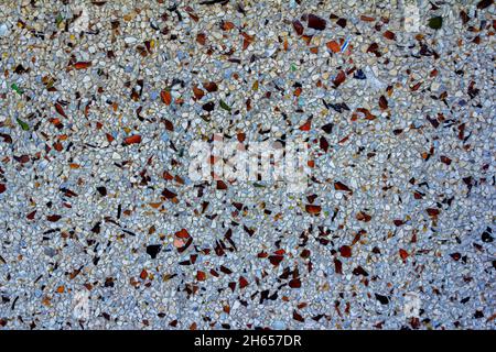 Sfondo astratto – parete della facciata in piccole pietre e pezzi di vetro marrone. Foto Stock