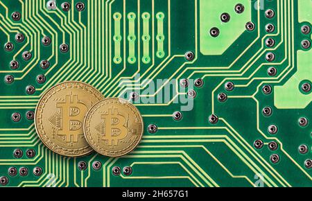 Moneta d'oro Bitcoin sul circuito stampato verde del computer Foto Stock