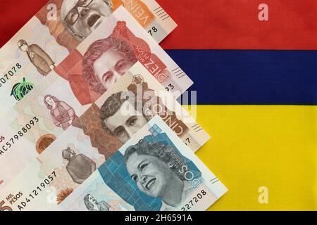 Denaro colombiano, banconote in pesos sullo sfondo della bandiera nazionale della Colombia Foto Stock