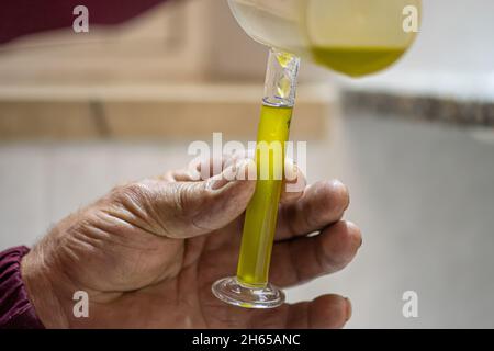 Produzione di olio extravergine di oliva ecologico con tecnologia moderna, estrazione e filtrazione, olio di oliva puro in una fiala di vetro Foto Stock